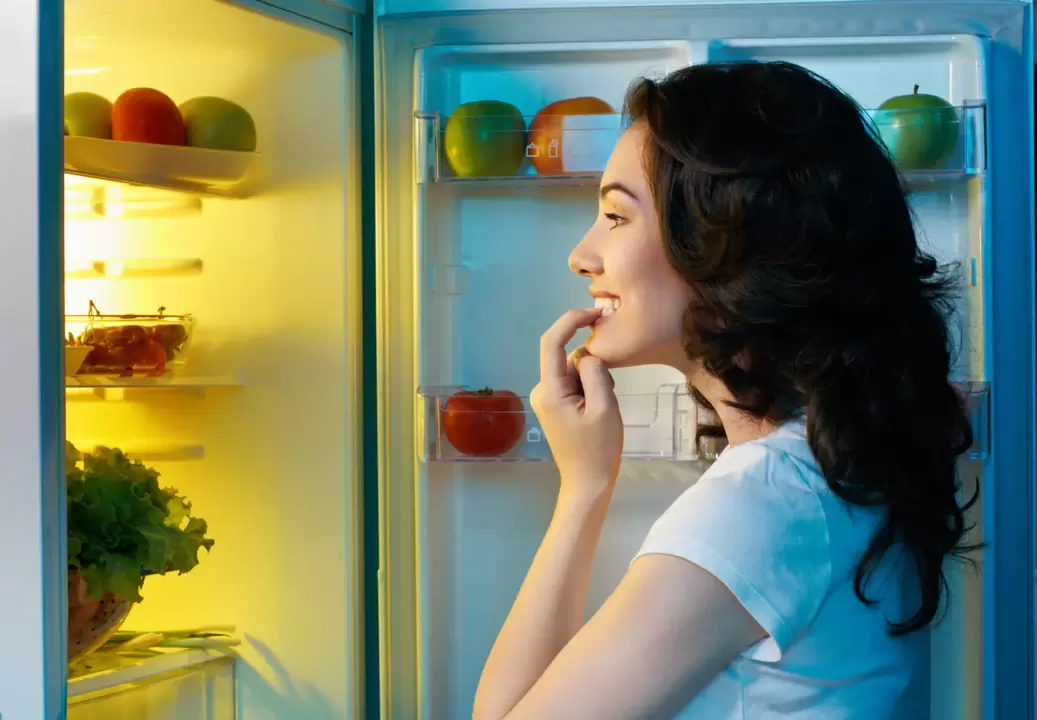 κορίτσι κοιτάζει στο ψυγείο κατά τη διάρκεια της γρήγορης απώλειας βάρους